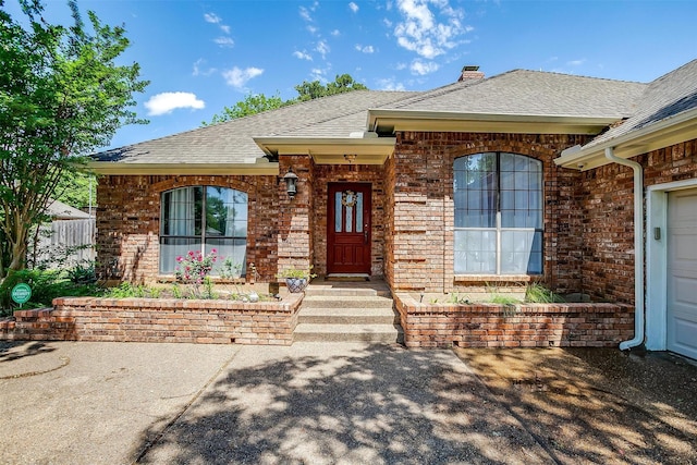 view of front of property featuring brick siding, a shingled roof, and a chimney