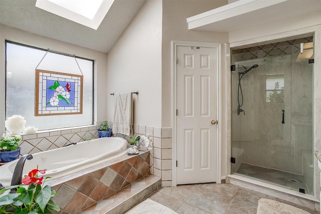 full bathroom featuring vaulted ceiling with skylight, a shower stall, and a garden tub