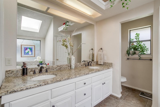 full bathroom featuring double vanity, a wealth of natural light, toilet, and a sink