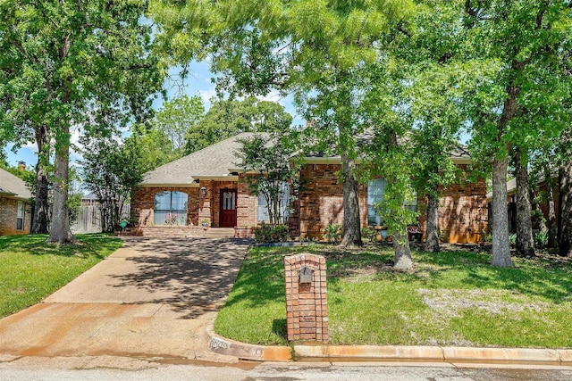 view of front of home with brick siding, a shingled roof, a front lawn, and concrete driveway