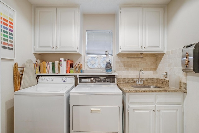 clothes washing area featuring washing machine and dryer, cabinet space, and a sink