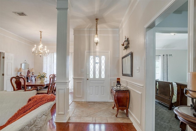 foyer entrance with a notable chandelier, a decorative wall, ornamental molding, and plenty of natural light