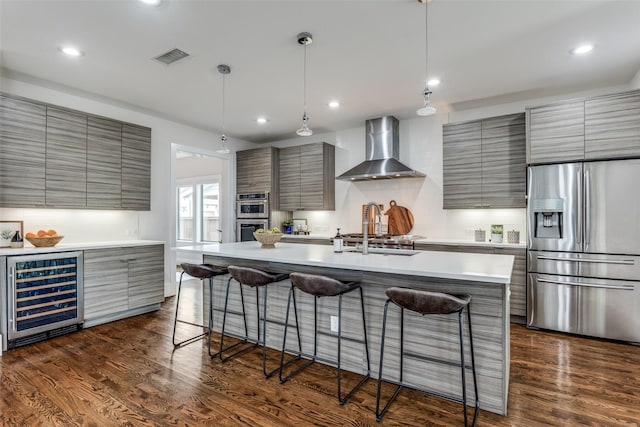 kitchen featuring beverage cooler, wall chimney range hood, stainless steel appliances, and modern cabinets