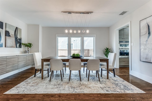 dining room featuring dark wood finished floors, visible vents, and baseboards