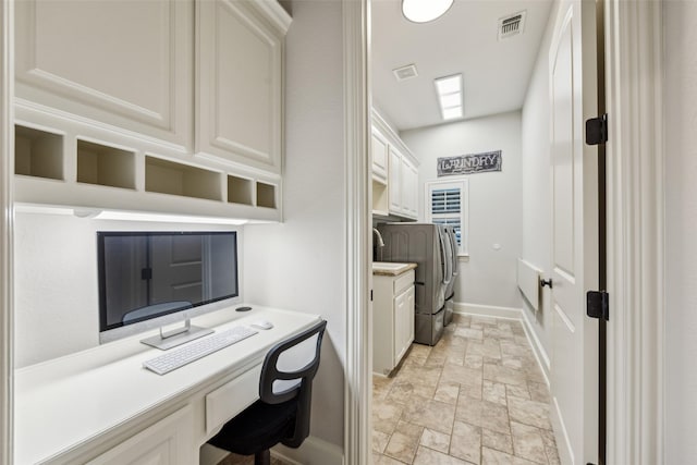 office area featuring washing machine and clothes dryer, stone tile floors, visible vents, baseboards, and built in study area