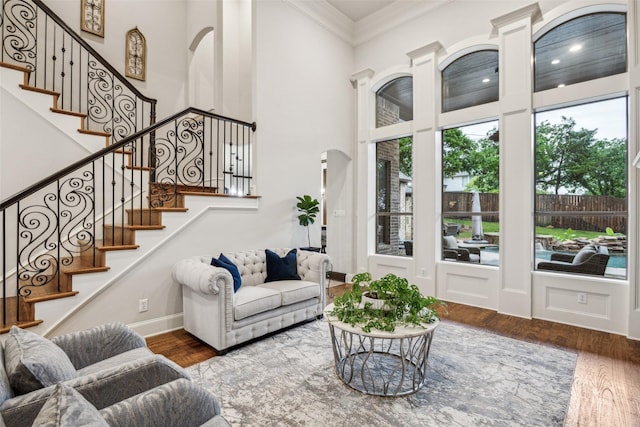 living area featuring baseboards, a wealth of natural light, ornamental molding, and wood finished floors