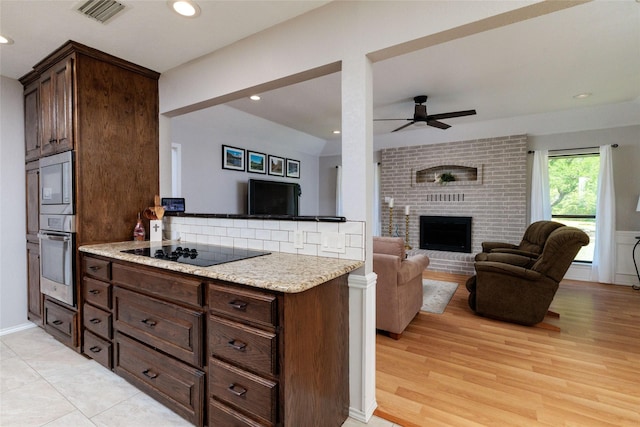 129 Highland Dr, Aledo, TX 76008 - kitchen with black electric stovetop, a brick fireplace, stainless steel oven, open floor plan, and visible vents