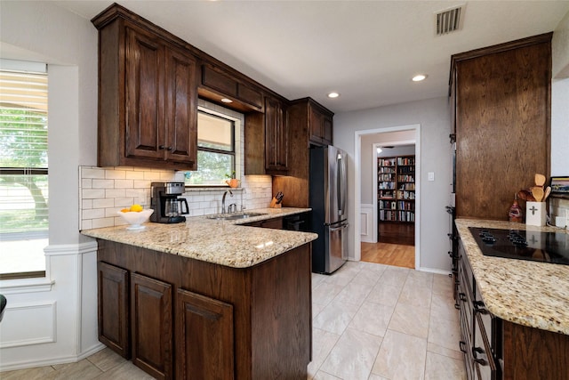 129 Highland Dr, Aledo, TX 76008 - kitchen featuring light stone counters, black electric stovetop, a sink, freestanding refrigerator, and a peninsula