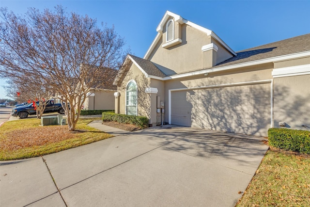 view of front facade featuring a garage, concrete driveway, and stucco siding