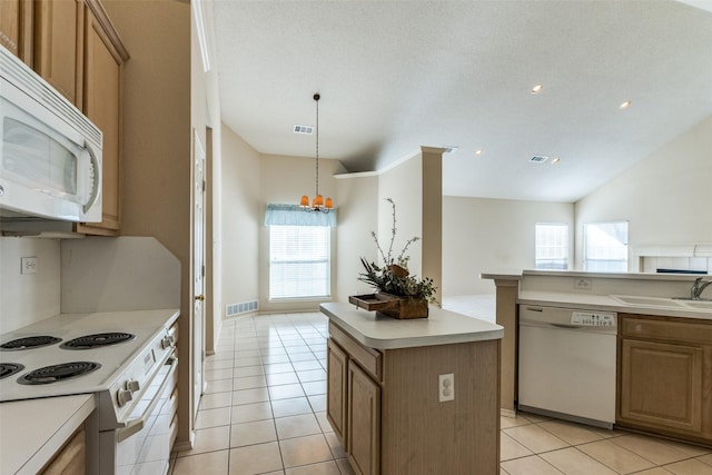 kitchen featuring a center island, a sink, plenty of natural light, visible vents, and white appliances