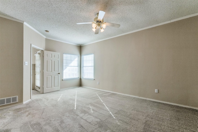carpeted spare room featuring crown molding, a ceiling fan, a textured ceiling, baseboards, and visible vents