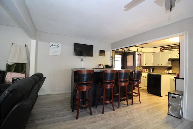 1281 W Eden St, Munday, TX 76371 - bar with bar, light wood-style floors, black dishwasher, ceiling fan, and under cabinet range hood