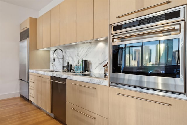 2200 Victory Ave Unit 2003, Dallas, TX 75219 - kitchen with appliances with stainless steel finishes, light brown cabinets, a sink, tasteful backsplash, and light wood-style flooring