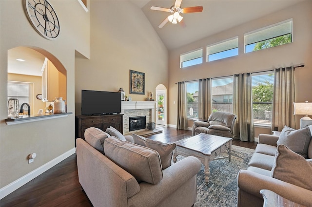 living area featuring arched walkways, high vaulted ceiling, dark wood-type flooring, and ceiling fan
