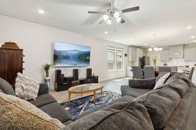 living room with baseboards, ceiling fan with notable chandelier, light wood-type flooring, and recessed lighting