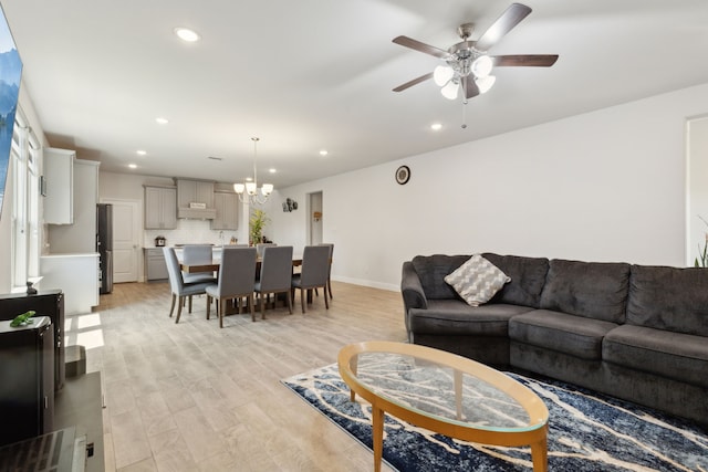 living room featuring recessed lighting, light wood-style floors, and ceiling fan with notable chandelier