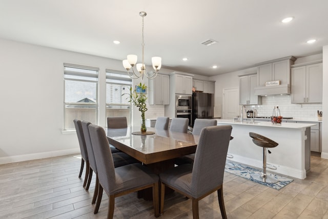 dining area with a chandelier, light wood-style floors, baseboards, visible vents, and recessed lighting
