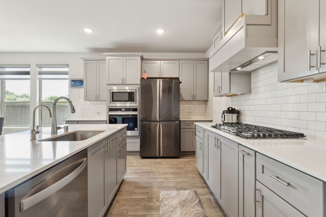 kitchen with stainless steel appliances, light countertops, gray cabinetry, and a sink