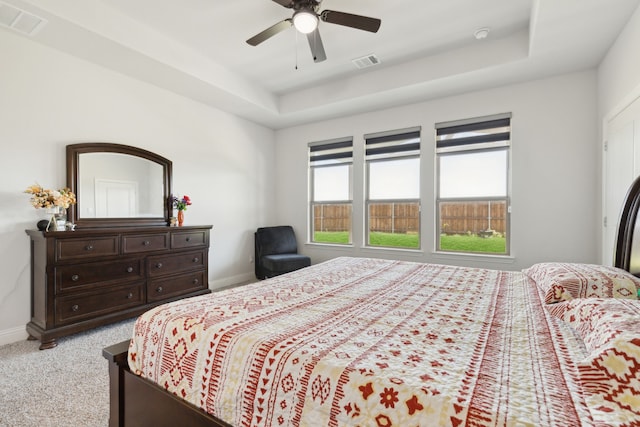 bedroom with light colored carpet, baseboards, a tray ceiling, and visible vents