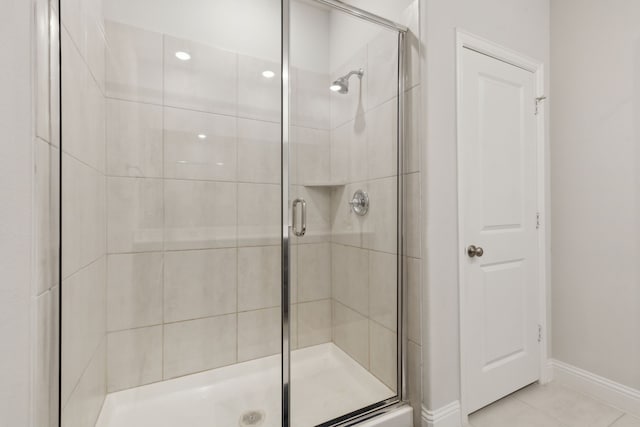 full bath featuring baseboards, tile patterned flooring, and a shower stall