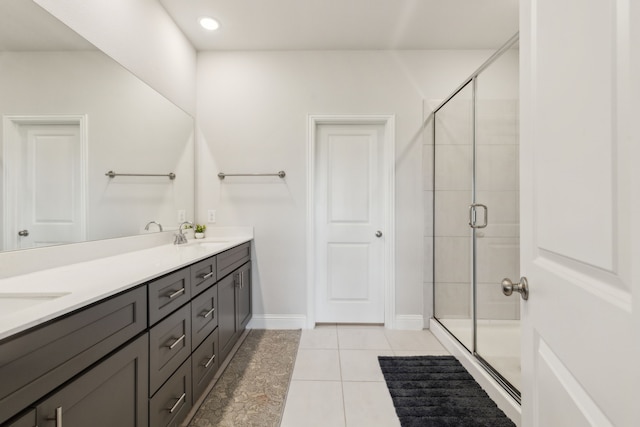 full bath featuring a shower stall, tile patterned floors, double vanity, and a sink