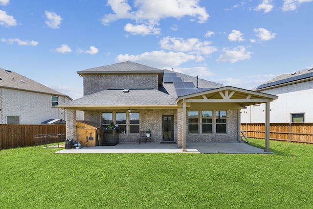 rear view of house featuring a patio area, brick siding, roof with shingles, and solar panels
