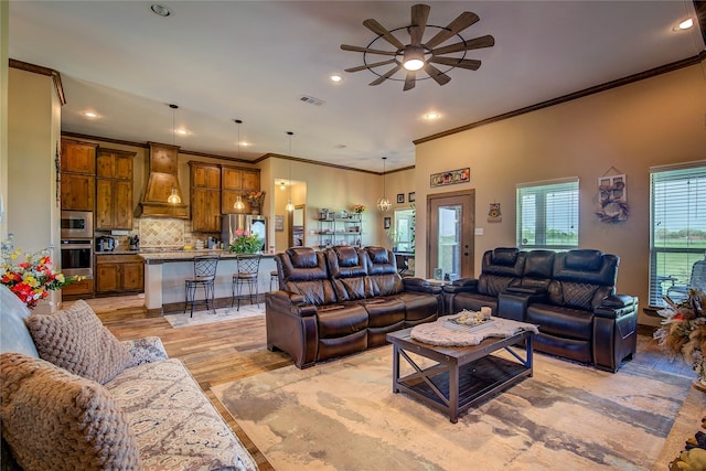 living room featuring ceiling fan, crown molding, and light wood-style floors