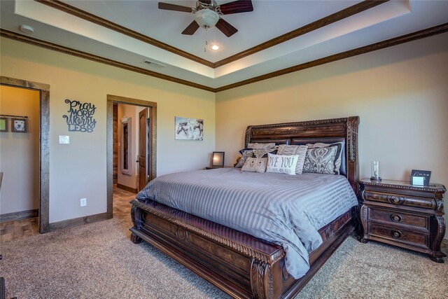 bedroom featuring crown molding, carpet floors, a raised ceiling, baseboards, and visible vents