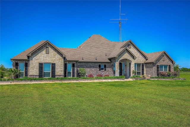 french country inspired facade with stone siding, a front lawn, and brick siding
