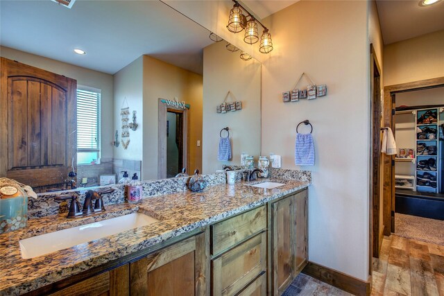 full bathroom with recessed lighting, double vanity, wood finished floors, and a sink