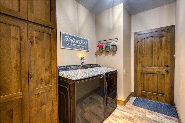 washroom featuring washer and clothes dryer, light wood-style floors, and cabinet space