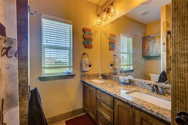 bathroom featuring visible vents, a sink, double vanity, and toilet