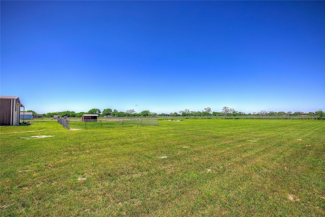 view of yard with a rural view, central AC, and fence