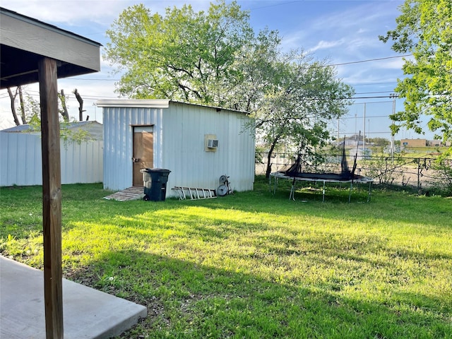 view of yard featuring an outdoor structure, a trampoline, and fence