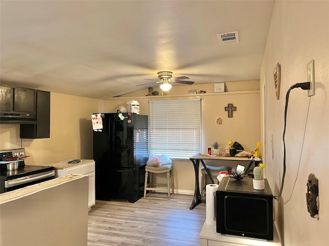 kitchen featuring a ceiling fan, stainless steel range with electric stovetop, under cabinet range hood, visible vents, and freestanding refrigerator