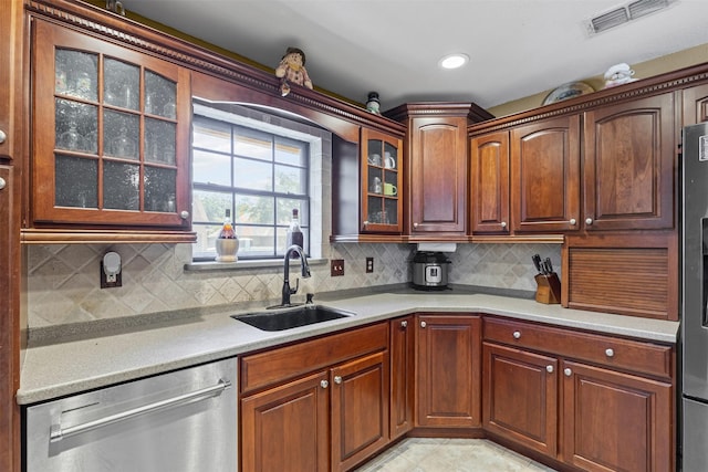 kitchen with a sink, glass insert cabinets, stainless steel appliances, light countertops, and visible vents