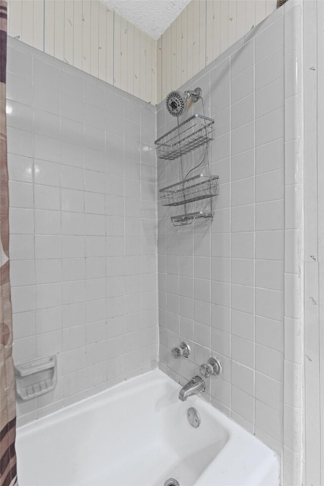 bathroom featuring a textured ceiling and shower / bathtub combination with curtain