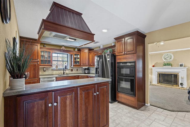 kitchen featuring a sink, decorative backsplash, glass insert cabinets, a peninsula, and appliances with stainless steel finishes