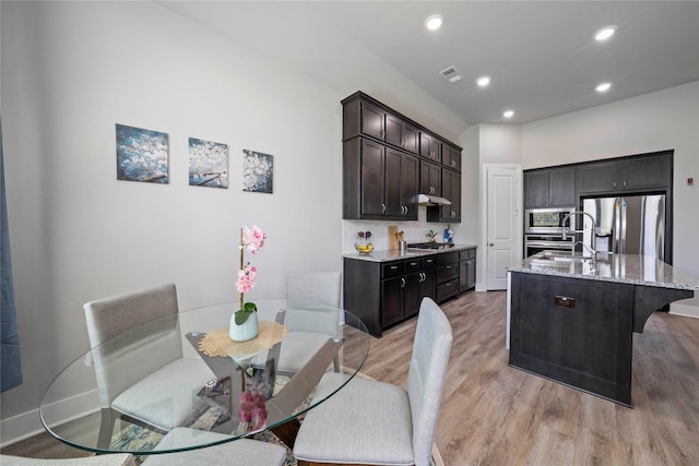 kitchen with stainless steel appliances, a sink, light wood-type flooring, recessed lighting, and light stone countertops