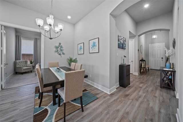 dining room with light wood finished floors, arched walkways, baseboards, an inviting chandelier, and recessed lighting