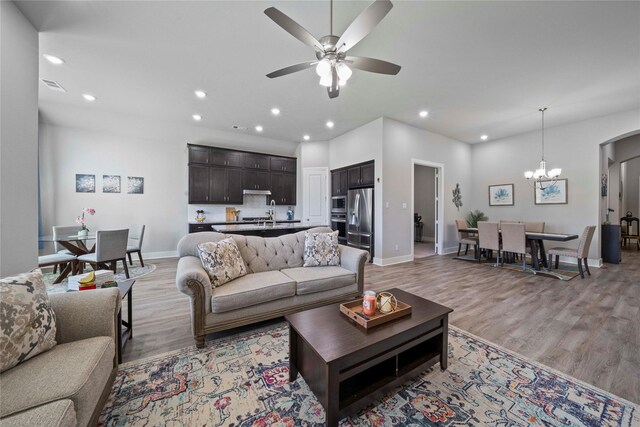 living area with light wood-type flooring, baseboards, recessed lighting, visible vents, and ceiling fan with notable chandelier