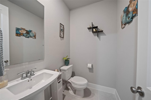 half bathroom with tile patterned floors, toilet, baseboards, and a sink