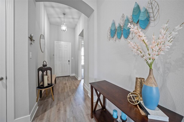 entrance foyer with arched walkways, wood finished floors, and baseboards