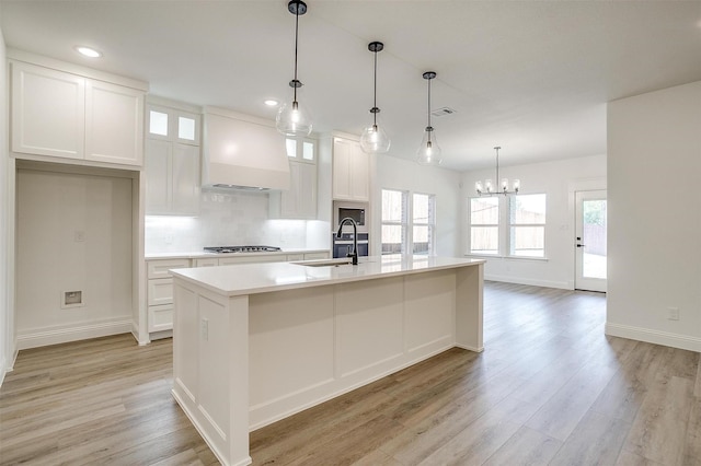 kitchen with premium range hood, white cabinetry, a chandelier, and light wood-style floors