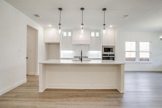 kitchen with light wood finished floors, light countertops, visible vents, and appliances with stainless steel finishes