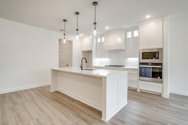 kitchen featuring custom exhaust hood, a sink, light wood-style floors, and appliances with stainless steel finishes