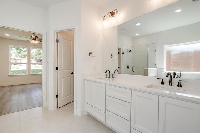 bathroom featuring double vanity, a shower stall, a ceiling fan, and a sink