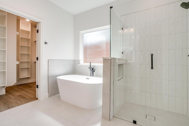 full bath with a walk in closet, a tile shower, and a soaking tub