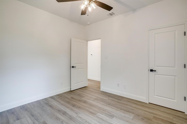 spare room with light wood finished floors, visible vents, a ceiling fan, and baseboards