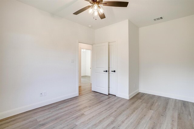 unfurnished bedroom with baseboards, a ceiling fan, visible vents, and light wood-style floors